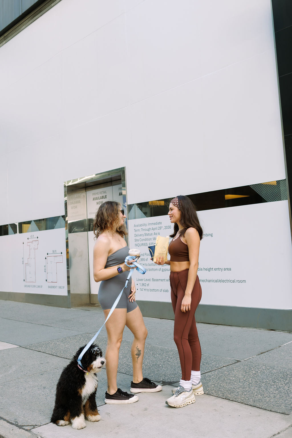 Two women in activewear with a dog on a New York sidewalk