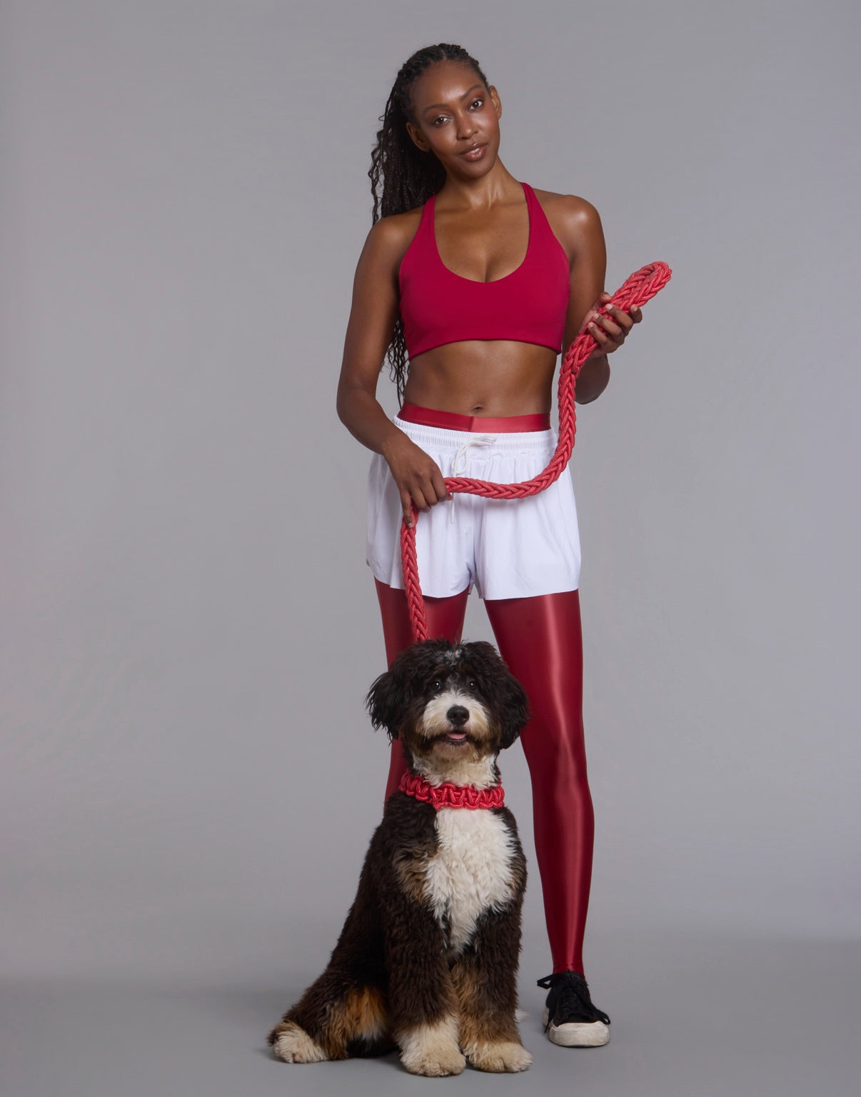 Woman in red activewear standing with a dog and matching rope leash