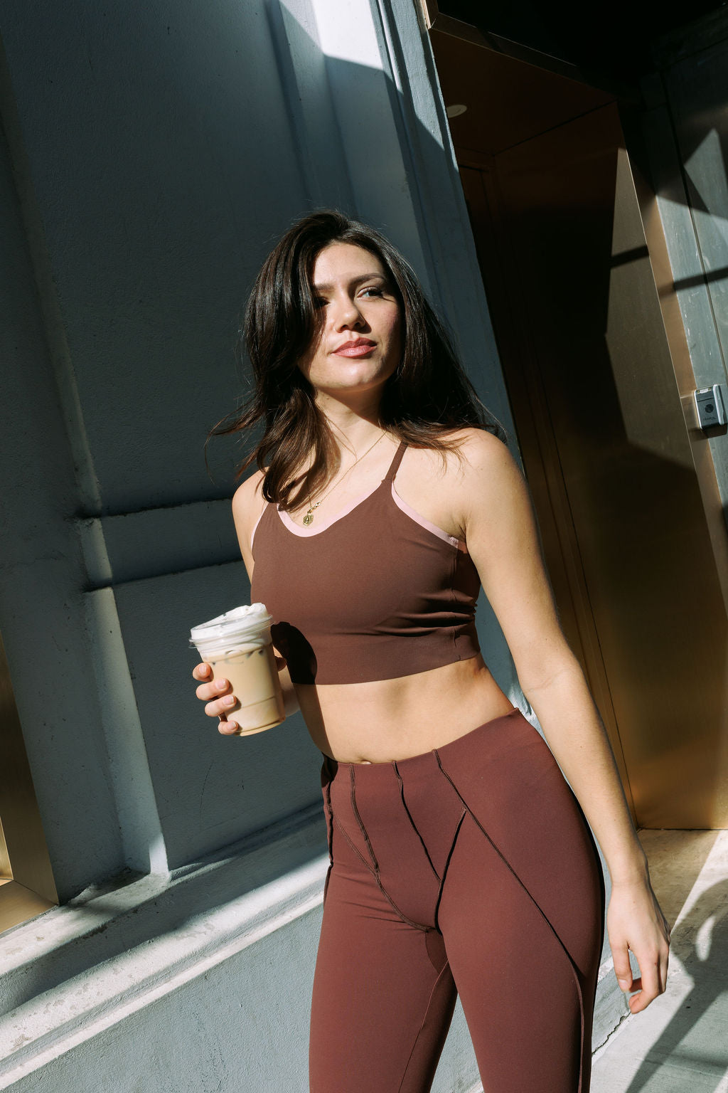 Woman in brown activewear holding an iced coffee in New York