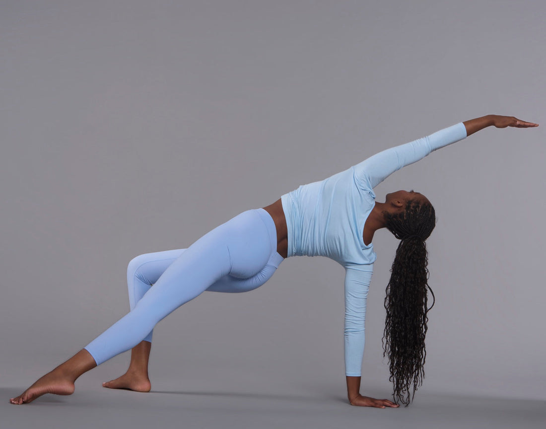 Woman in light blue activewear extending through a studio movement
