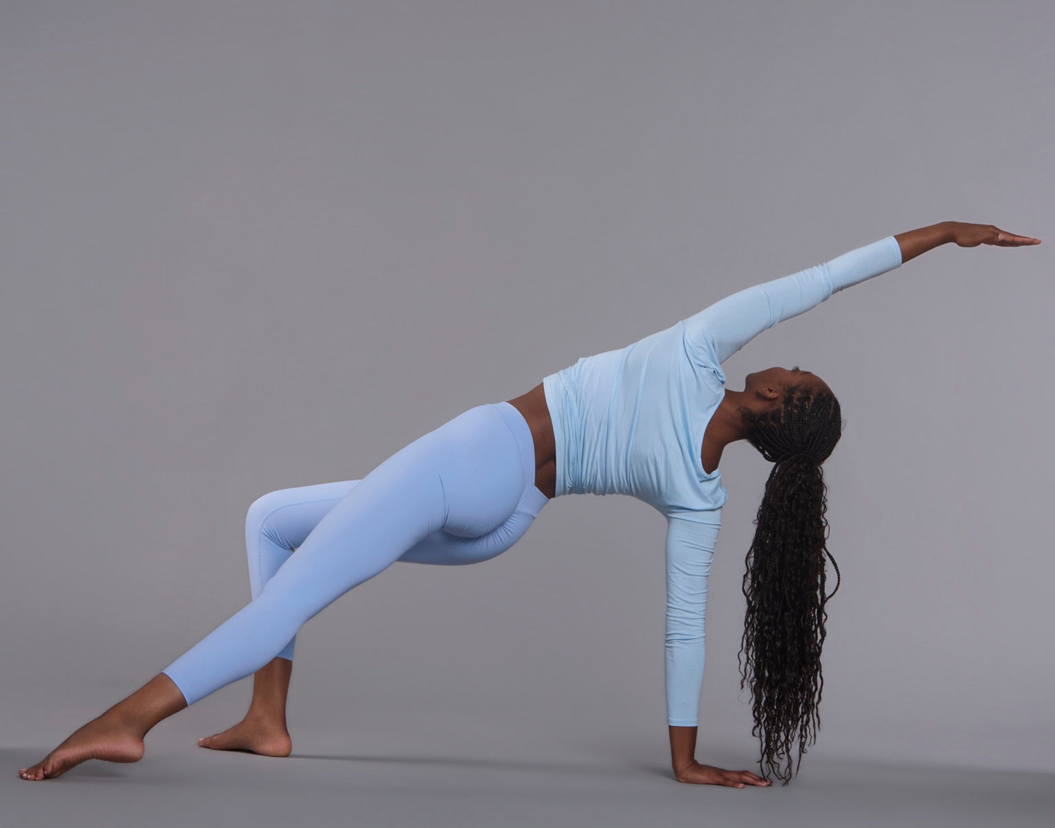 Woman in light blue activewear extending through a studio movement