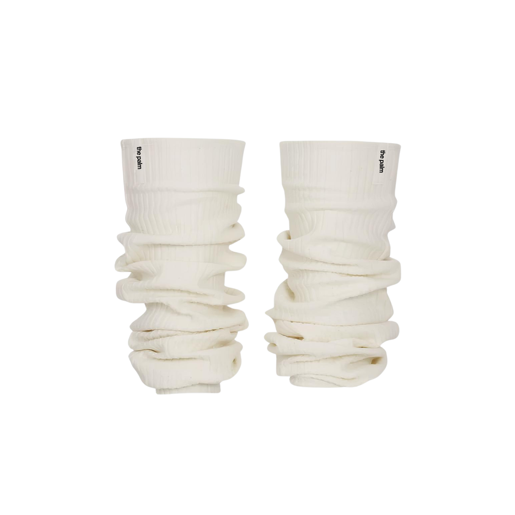 Ivory ribbed knit leg warmers by The Palm, featuring a minimalist logo tag and soft slouchy texture on a ivory white background1