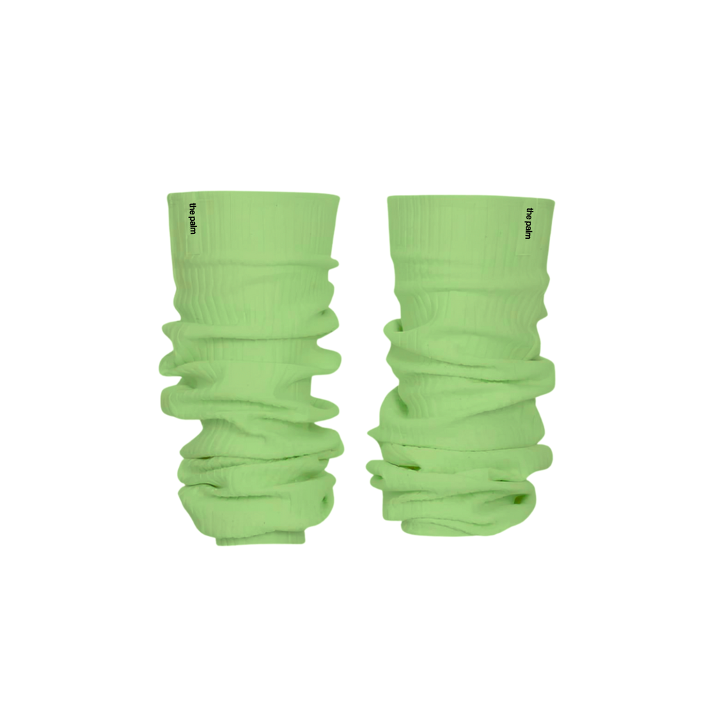 Ivory ribbed knit leg warmers by The Palm, featuring a minimalist logo tag and soft slouchy texture on a mint green background1