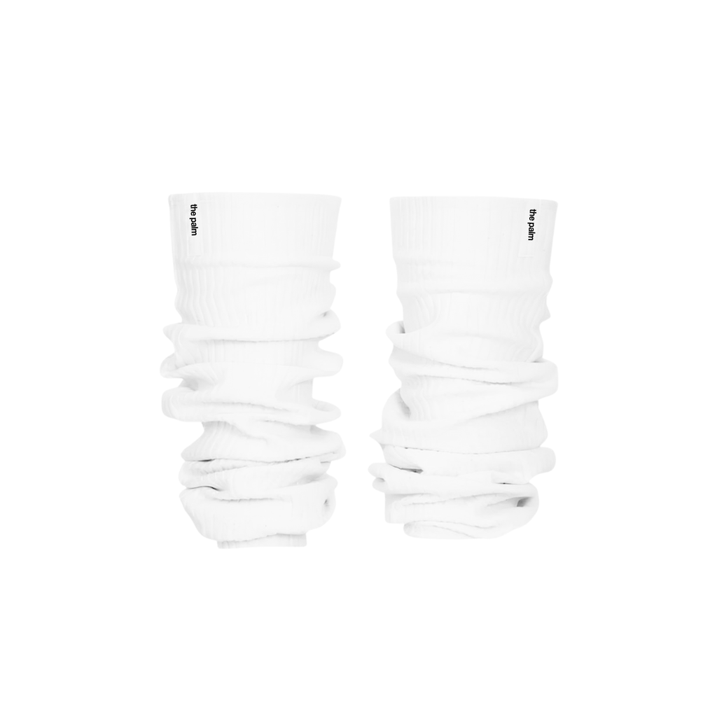 Ivory ribbed knit leg warmers by The Palm, featuring a minimalist logo tag and soft slouchy texture on a white background.