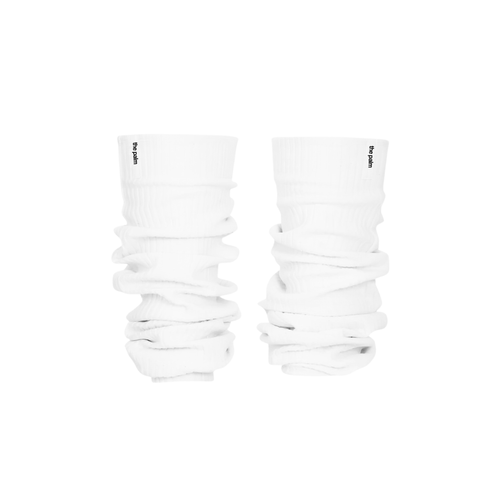 Ivory ribbed knit leg warmers by The Palm, featuring a minimalist logo tag and soft slouchy texture on a white background.