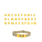 A grid displaying the complete alphabet and special symbols (heart, flower, star, paw) all in yellow, with a separate dog collar showing an example of how the yellow letters are attached to create a personalized name.