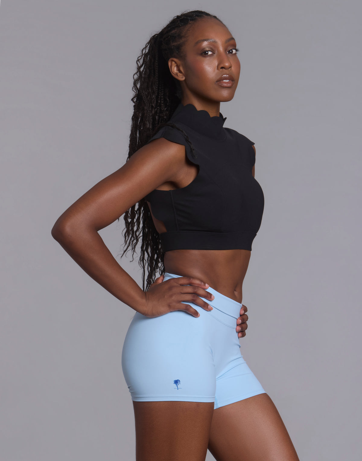Three-quarter studio view of woman wearing black CloudPetal mock neck top and light blue shorts