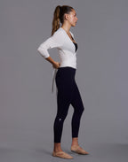 Side profile full-length view of woman wearing white WrapLuxe cropped long sleeve wrap top with black leggings