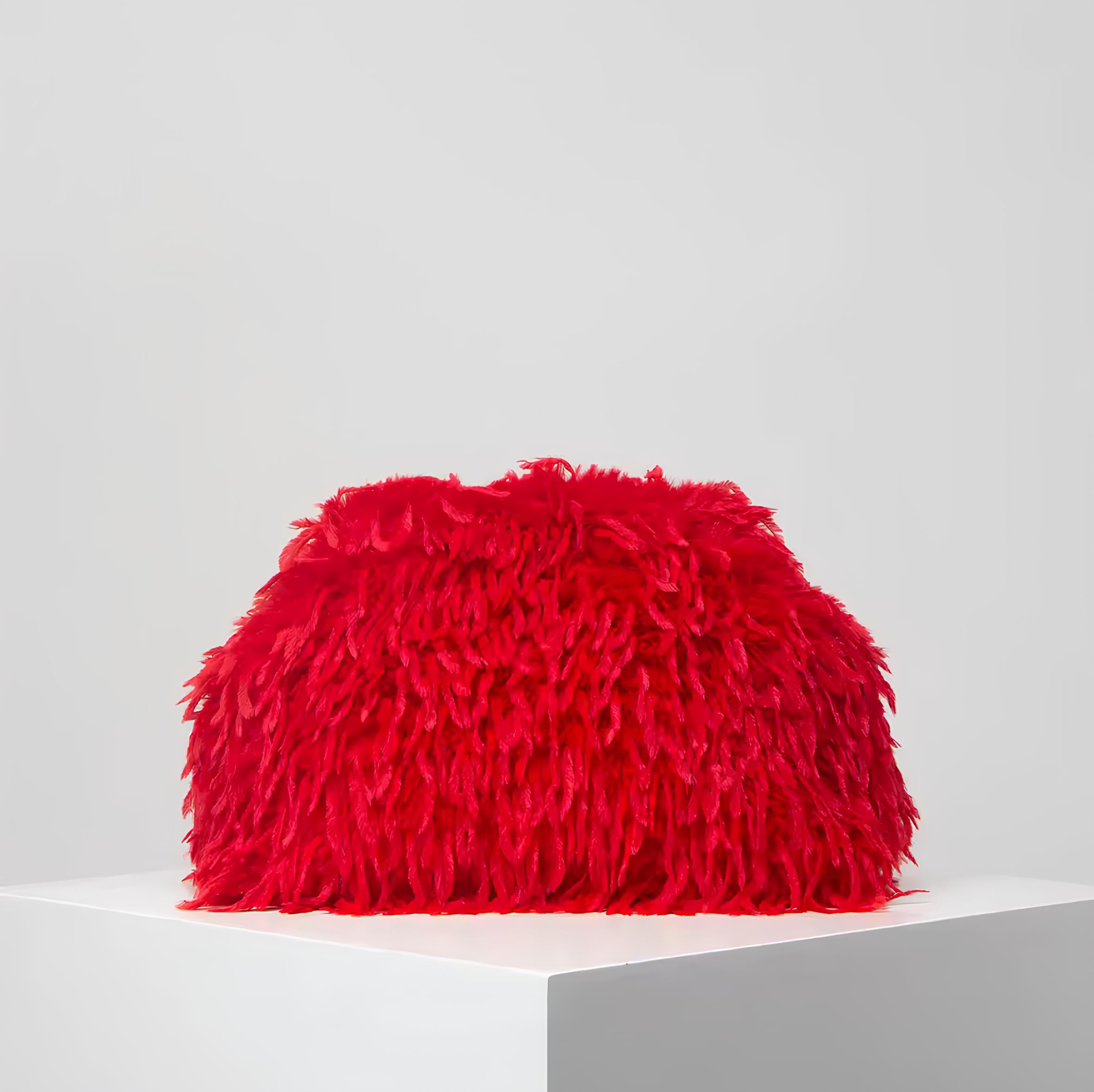 The Palm FeatherLuxe™ bag in Fire Sculpt. Plush feather-textured clutch in a vivid sculpted red tone, designed as a bold statement piece with refined silhouette.